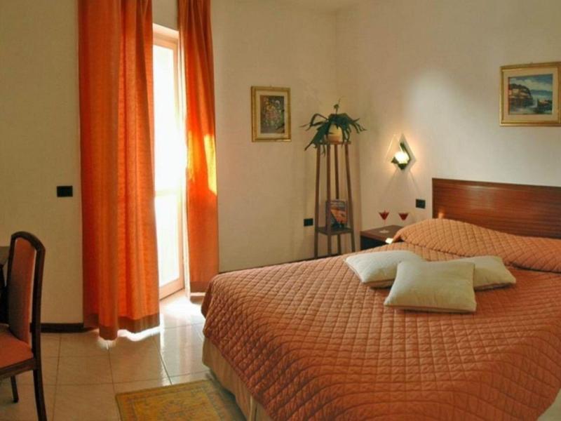 Bedroom with large bed, orange curtains, TV, and small desk.