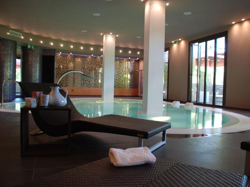 Modern indoor pool with relaxing atmosphere, lounge chairs, and large windows.