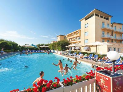 Hotel mit großem Außenpool und Gästen, die bei sonnigem Wetter schwimmen und entspannen.