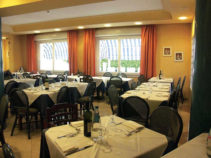 Licht ingericht eetzaal met gedekte tafels en oranje gordijnen in een hotel.