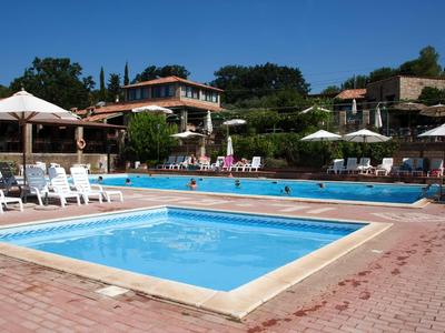 Hotelpool mit Sonnenschirmen und Liegestühlen in einer sonnigen Umgebung mit Gebäuden im Hintergrund