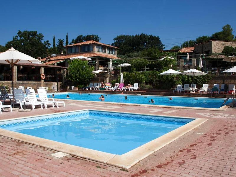 Zwei rechteckige Schwimmbecken mit klarem Wasser umgeben von Liegestühlen und Sonnenschirmen.