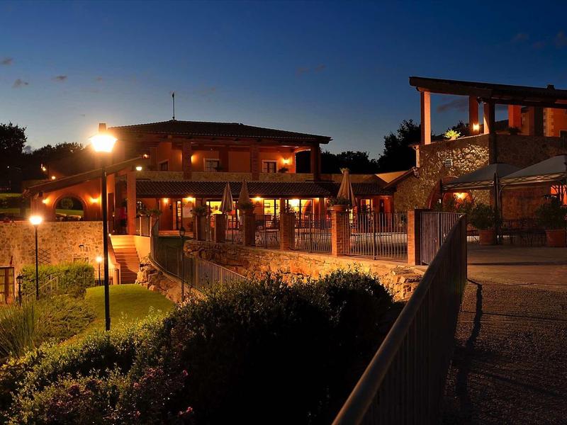 Beleuchtetes modernes Gebäude mit Terrasse und Stufen bei dämmerndem Himmel in warmen Farbtönen.