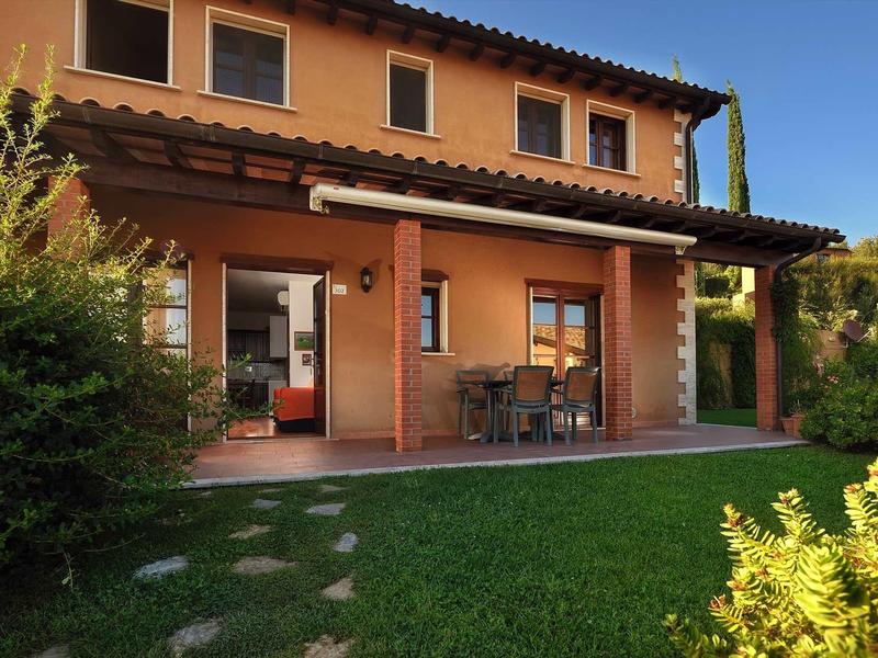 Modernes zweistöckiges Haus mit oranger Fassade, großem Garten und Terrasse bei klarem Himmel.