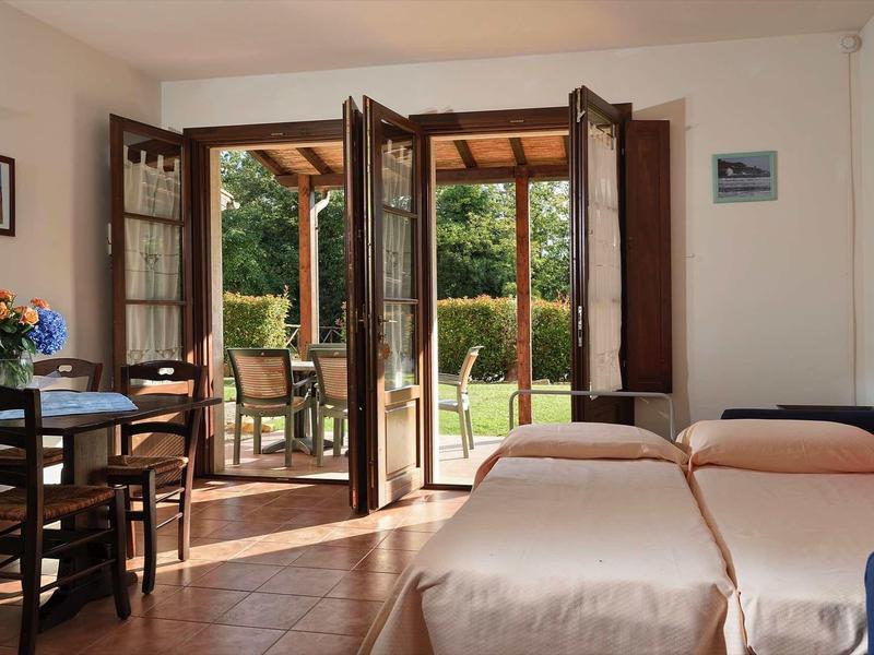 Hell eingerichtetes Wohnzimmer mit offenen Holztüren zum grünen Garten und gemütlichen Möbeln.