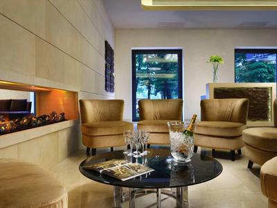 Modernes Wohnzimmer mit beigen Sesseln, rundem Glas-Tisch und eingebautem Kamin.