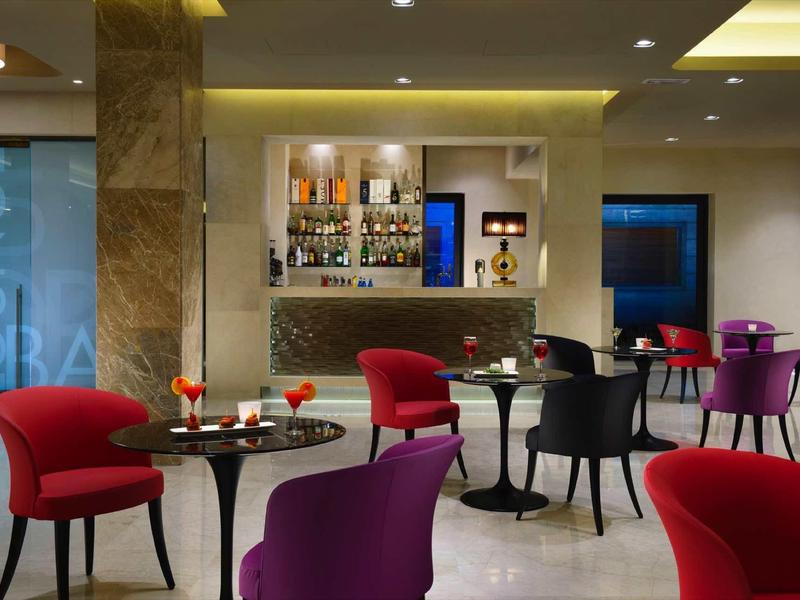 Moderne Lounge mit farbigen Sesseln in Rot, Lila, Schwarz und kleinen runden Tischen.