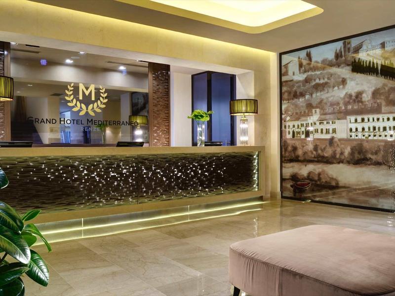 Moderne Hotellobby mit beleuchtetem Empfangstresen, großen Wandbildern und gemütlicher Sitzbank.