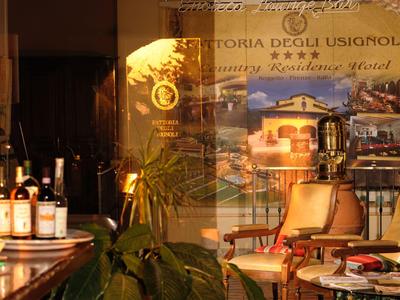 Bar accogliente con bottiglie di vino, sedie e piante in luce calda.