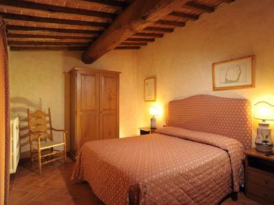 Pohodlná ložnice s manželskou postelí, dřevěným stropem a teplým osvětlením.