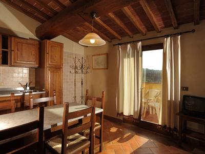 Rustikální jídelna s dřevěným stolem, židlemi, kuchyňskými skříňkami a dveřmi na balkon.