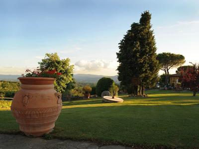 Großer Terrakotta-Blumentopf auf gepflegtem Rasen mit Bäumen und weiter Aussicht.
