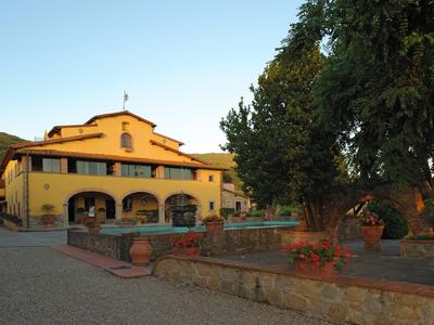 Casa di campagna gialla con terrazza e alberi al tramonto
