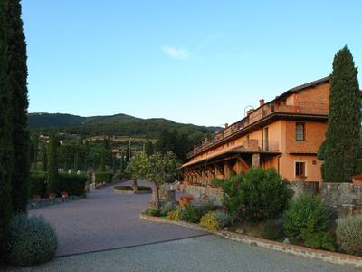Un grande edificio dell'hotel accanto a un giardino curato con montagne sullo sfondo.