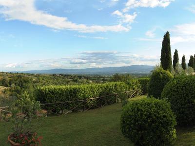 Prostorná zahrada s bazénem, trávníkem, keři a stromy pod modrou oblohou.