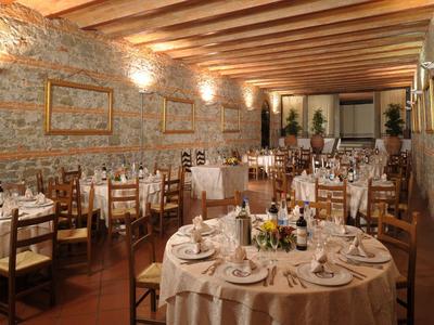 Elegantní restaurace s rustikální kamennou zdí a prostřenými kulatými stoly.