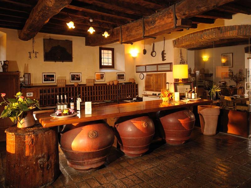 Příjemný bar s rustikálním dřevěným interiérem a velkými hlíněnými nádobami pod pultem.