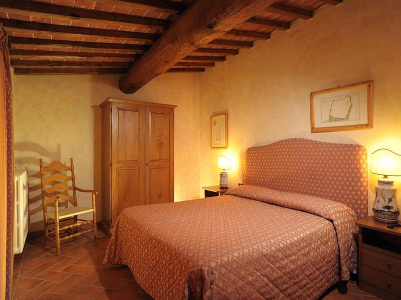 Pohodlná ložnice s manželskou postelí, dřevěným stropem a teplým osvětlením.