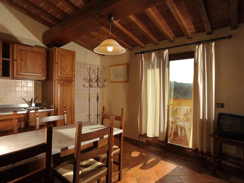 Rustikální jídelna s dřevěným stolem, židlemi, kuchyňskými skříňkami a dveřmi na balkon.