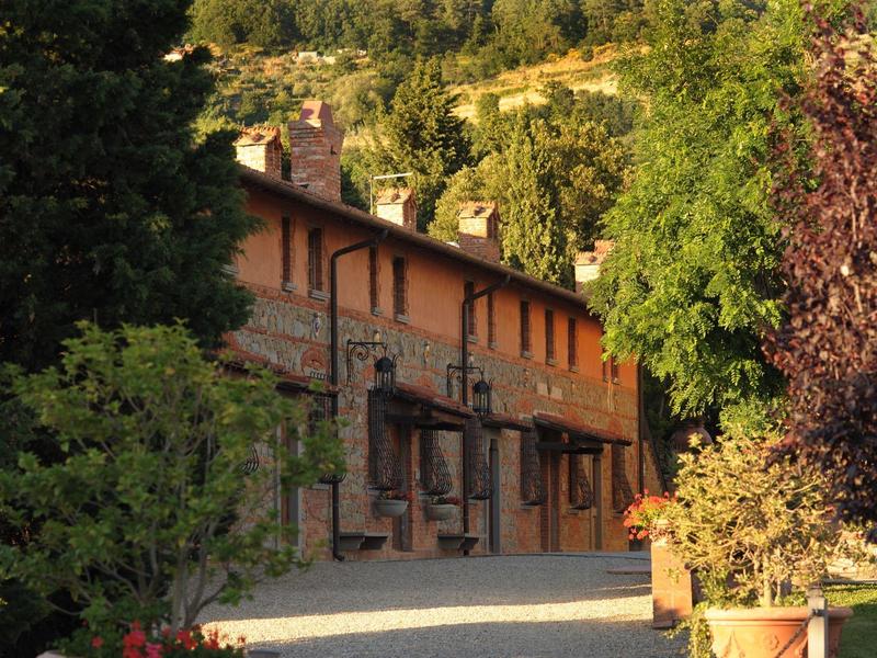 Rustikální budova v venkovském prostředí obklopená stromy a kopci.