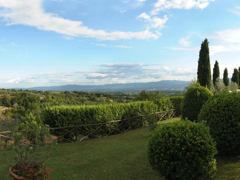 Prostorná zahrada s bazénem, trávníkem, keři a stromy pod modrou oblohou.