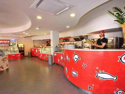Vista interior de un bar de hotel colorido con mostrador rojo y decoración.
