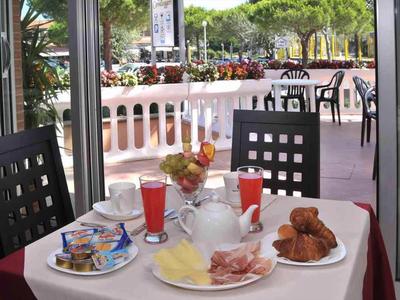 Mesa con platos de desayuno, bebidas y zona de asientos con vista a la terraza y al jardín.