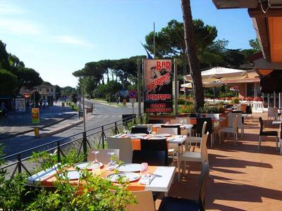 Terraza de restaurante con mesas puestas junto a una calle tranquila a la luz del día