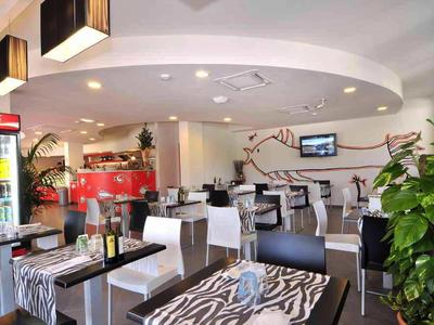 Ristorante moderno con tavoli a motivo zebra, sedie bianche e piante d'interni.