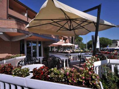 Terraza de hotel con sombrillas, mesas y sillas rodeadas de plantas.