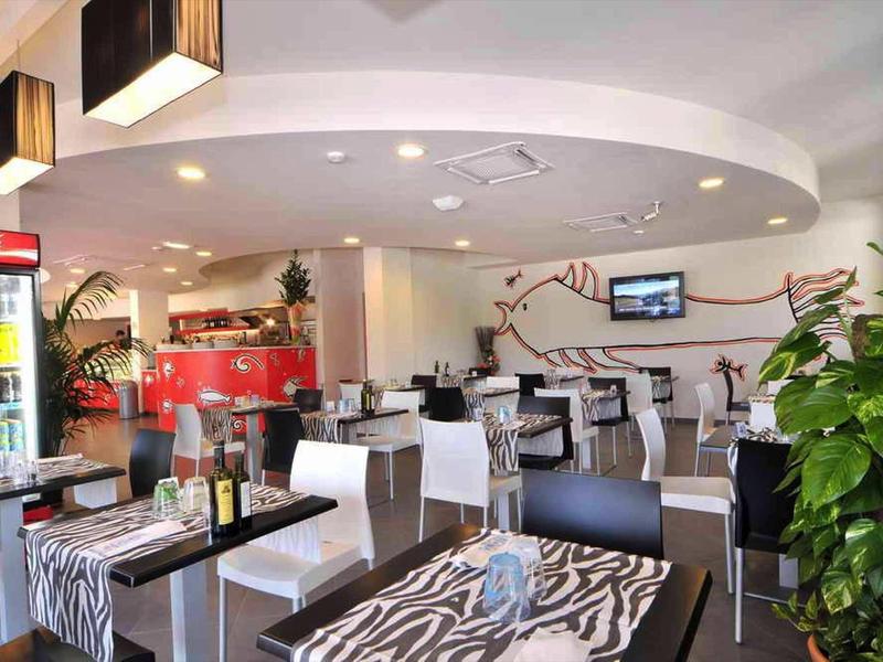 Ristorante moderno con tavoli a motivo zebra, sedie bianche e piante d'interni.