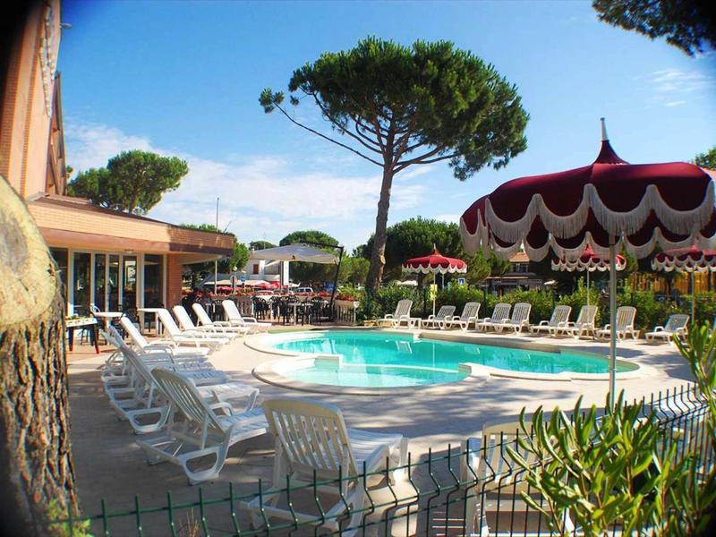 Piscina dell'hotel con ombrelloni, sdraio e alberi sullo sfondo