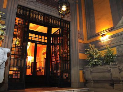 Hotelentree met open deuren, warm licht en planten aan de gevel.