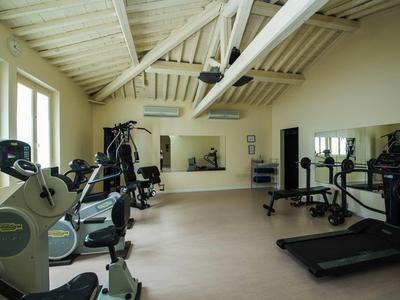 Lichte fitnessruimte met moderne apparatuur en wit houten balkenplafond.