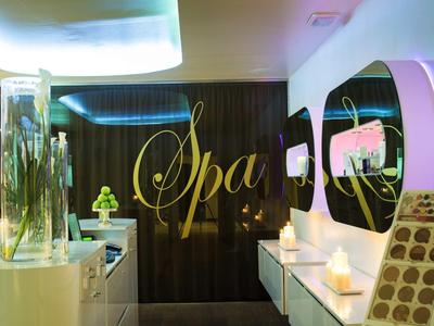 Moderner Spa-Bereich mit dunkler Wand, goldener Schrift, Spiegeln und sanfter Beleuchtung.