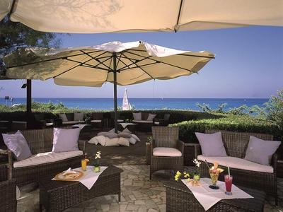 Przytulny lounge na zewnątrz z meblami z wikliny, parasolami i widokiem na morze.