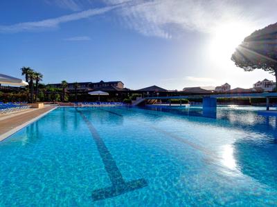 Grande piscina all'aperto con acqua azzurra limpida e lettini al sole.