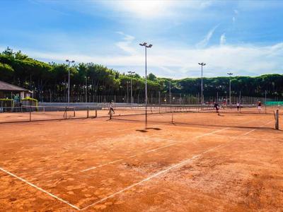 Un campo da tennis in terra rossa con due giocatori sotto il sole.
