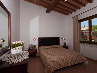 Příjemná ložnice s dřevěným trámovým stropem, manželskou postelí a výhledem na terasu.