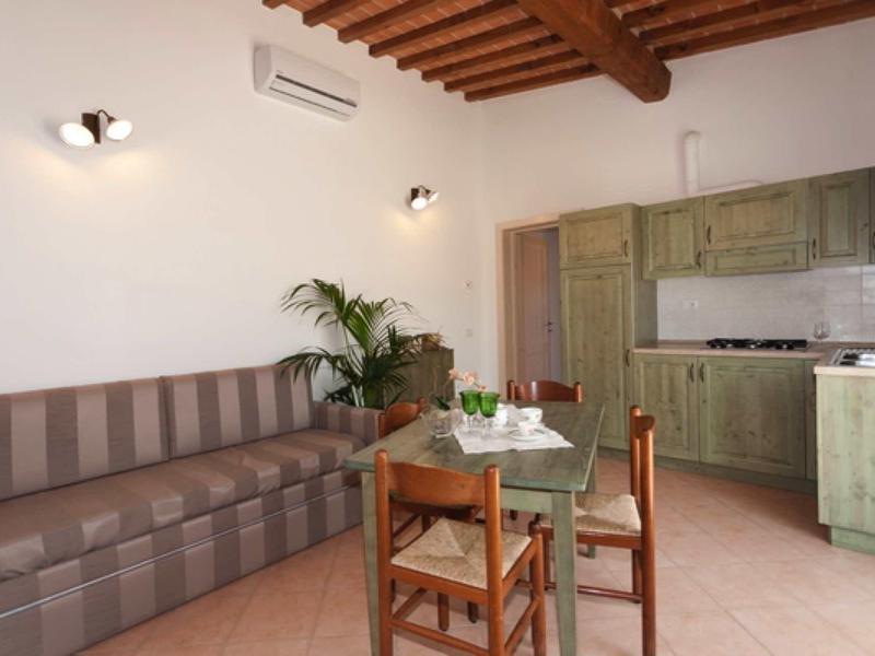 Přátelská kuchyň s dřevěným stropem, zelenou linkou a jídelním stolem se židlemi.