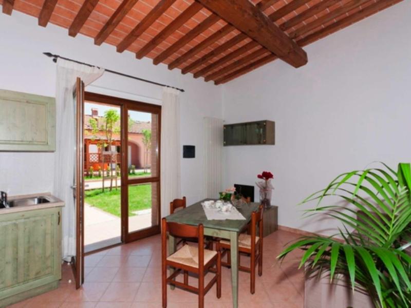 Jasná jídelna s dřevěným stolem, židlemi a výhledem do zahrady přes skleněné dveře.