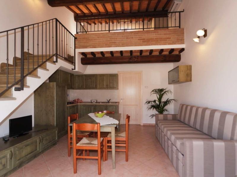 Světý obývací pokoj s dřevěným stropem, jídelním koutem, pohovkou a otevřenou kuchyní v rekreačním domě.