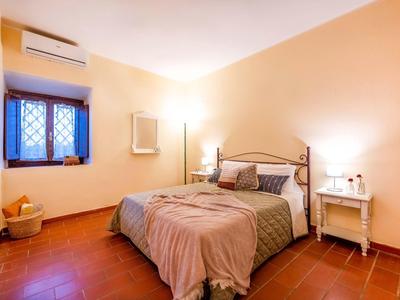 Pohodlná ložnice s manželskou postelí, nočním stolkem a oknem s mříží.