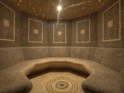 Prostorná hammam místnost s mozaikovými dlaždicemi a centrálním zaobleným sezením.