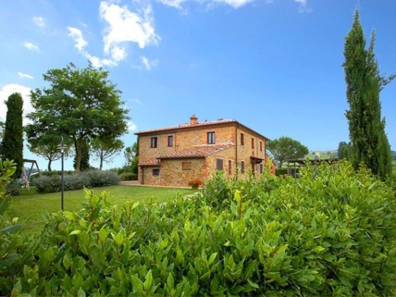 Kamenný venkovský dům v zelené krajině pod modrou oblohou.