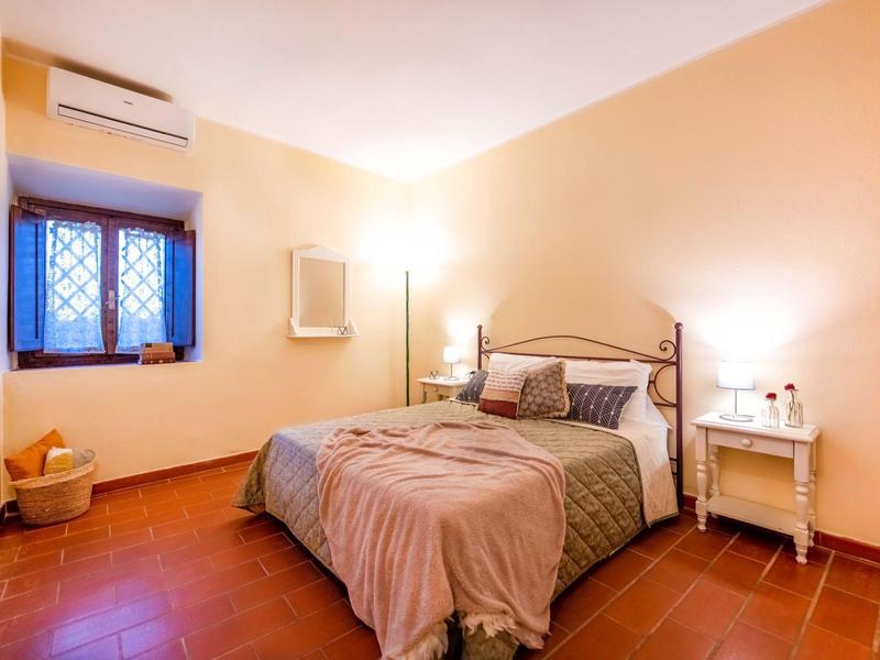 Pohodlná ložnice s manželskou postelí, nočním stolkem a oknem s mříží.