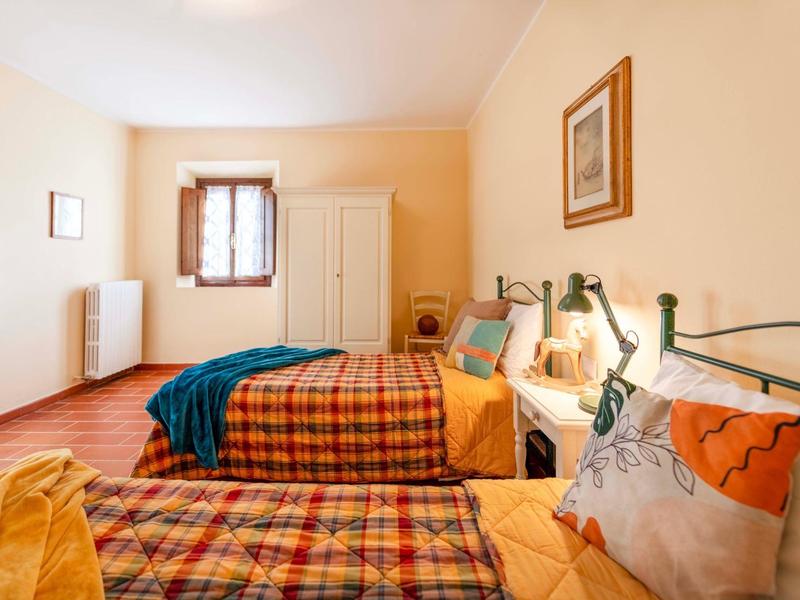 Světý hotelový pokoj se dvěma jednolůžky, dřevěnou podlahou a okny se slunečním světlem.