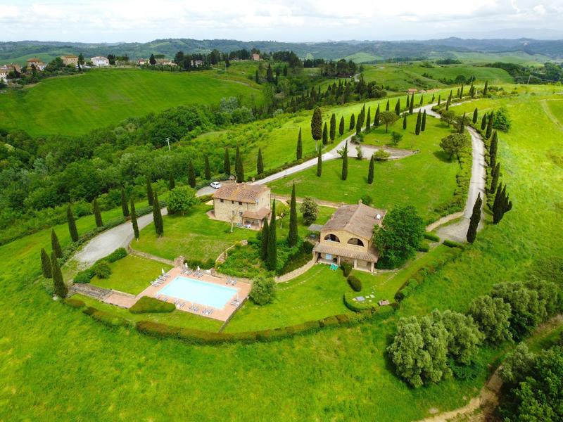 Venkovský statek se dvěma domy, bazénem a cypřišovými alejemi v zelené krajině.