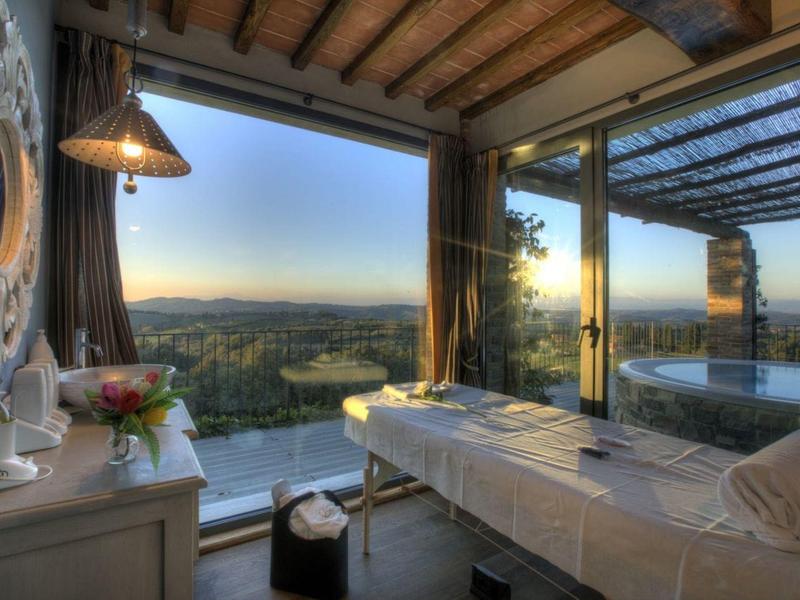 Pohodlný wellness pokoj s velkým oknem a výhledem na krajinu při západu slunce