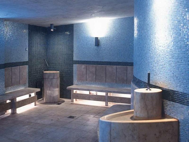 Interior of a blue wellness sauna with wooden benches and a bubbling fountain.